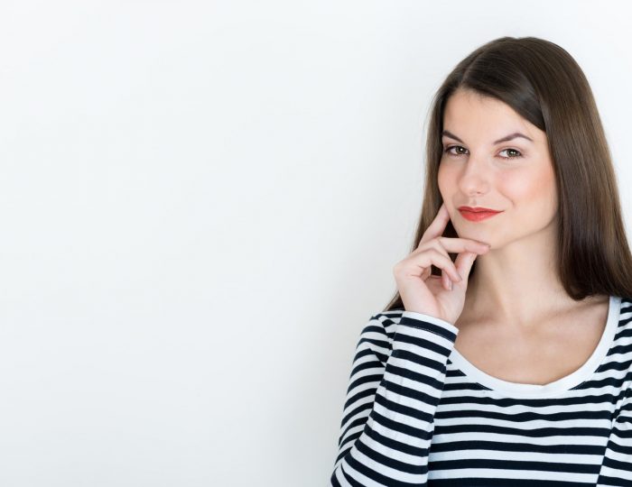 Attractive young woman deep in her thoughts, on white background