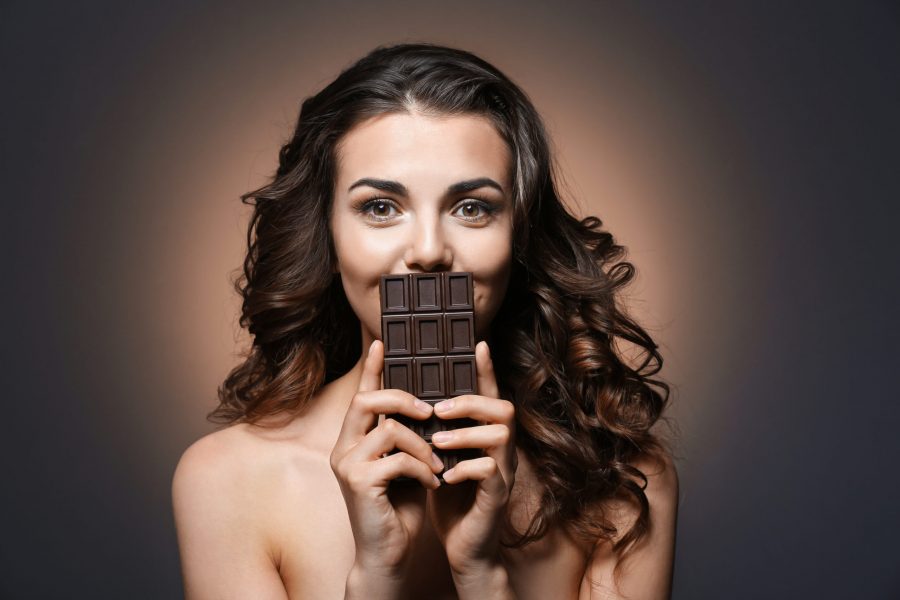 Beautiful girl with chocolate on dark background