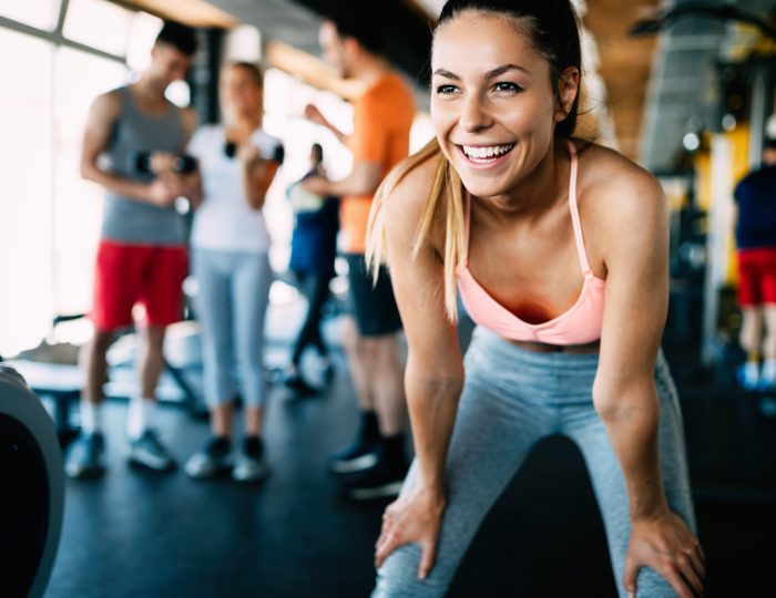Close up image of smiling attractive fit woman in gym