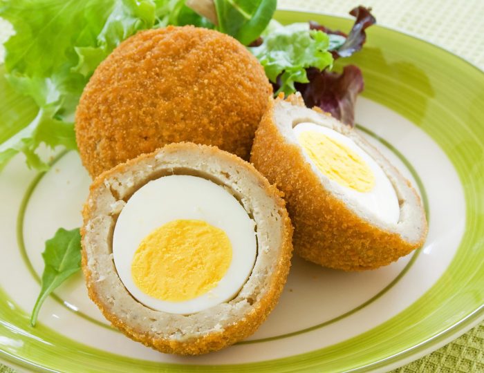 Scotch eggs on a plate with a green salad