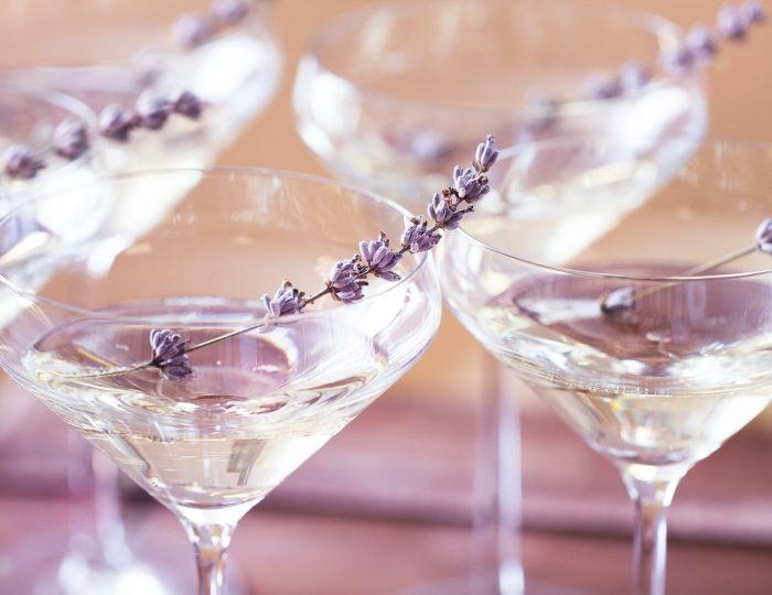 Glasses of with white champagne decorated with lavender on blurred background. DOF