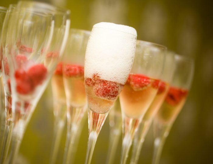 Champagne in glasses with fresh red raspberries